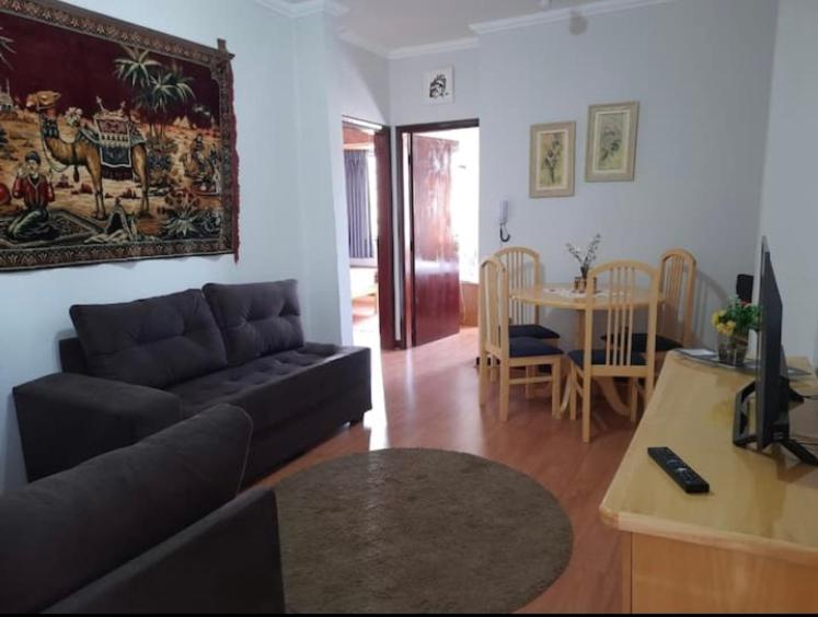 ein Wohnzimmer mit einem Sofa und einem Tisch in der Unterkunft Apartamento Central, quarto andar in Serra Negra