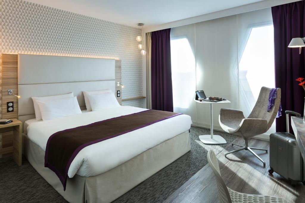 a hotel room with a large bed and a chair at Mercure Paris Orly Rungis Aéroport in Rungis