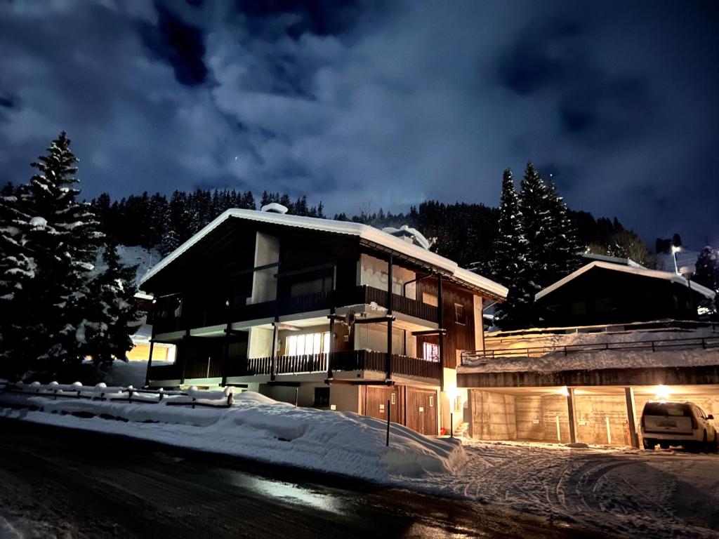 Una casa en la nieve por la noche en Casa Ucliva - Charming Alpine Apartment Getaway in the Heart of the Swiss Alps, en Rueras