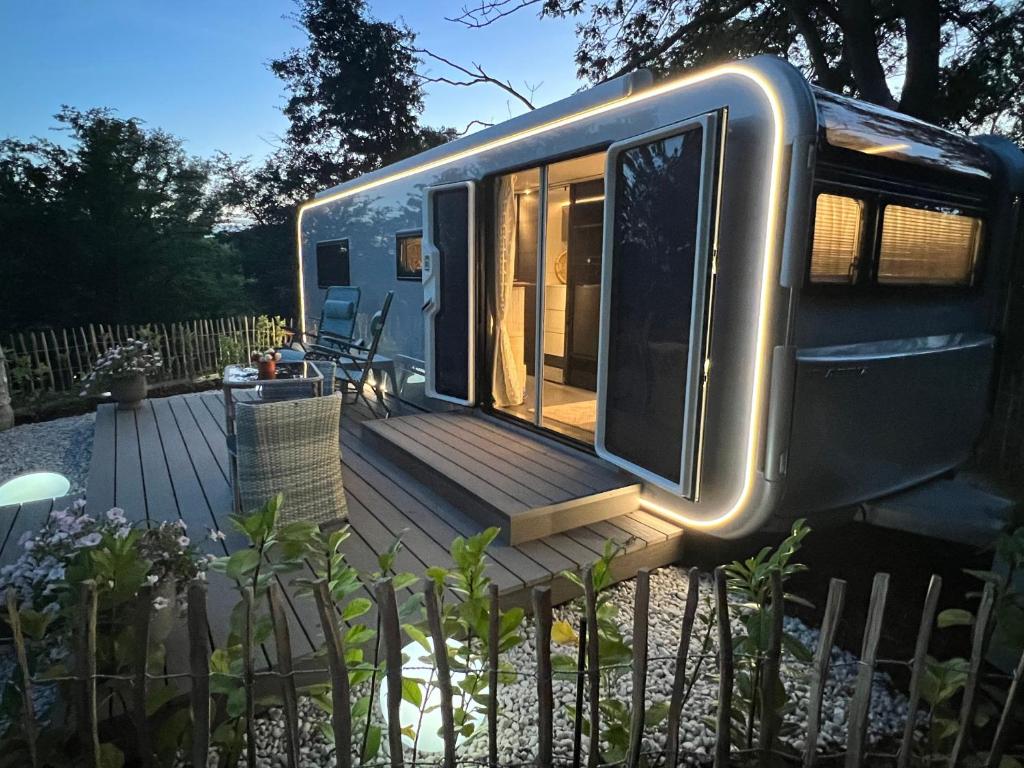 a trailer with a wooden deck in a yard at Luxuswohnwagen Dreamer mit Achterwasserblick in Lütow