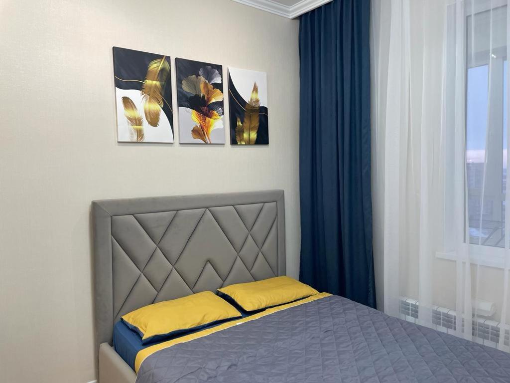 a bedroom with a bed with three pictures on the wall at Апартаменты Soul Park in Astana