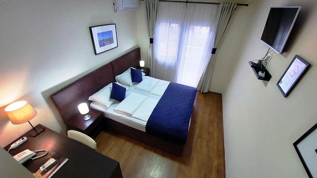 um pequeno quarto com uma cama e uma secretária com um telefone em Hotel Villa Panorama em Belgrado