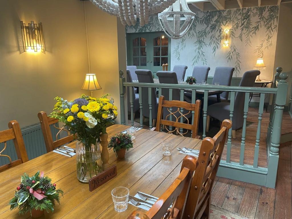 a dining room with a wooden table with flowers on it at The Golden Cross in Cirencester