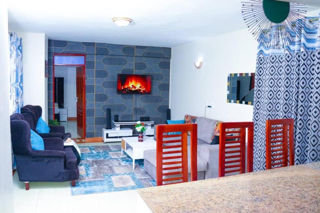 The porch garden Estate 1 bedrm في نيروبي: غرفة معيشة مع كراسي حمراء ومدفأة