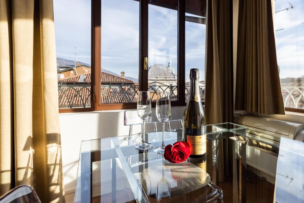 una mesa de cristal con dos botellas de vino y una rosa en ella en L'Altana City House, en Brescia
