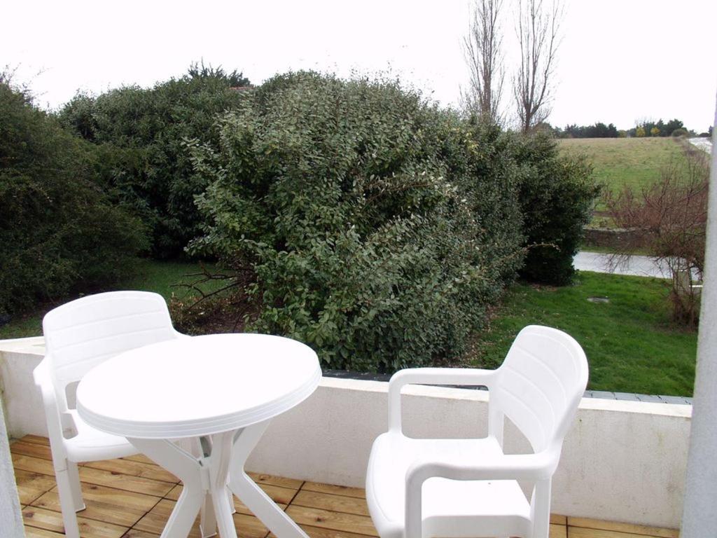 2 sillas blancas y una mesa en el patio en Appartement Le Palais, 2 pièces, 2 personnes - FR-1-418-165 en Le Palais
