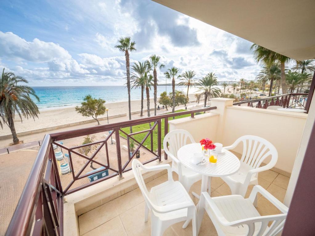 balcón con mesa y sillas y la playa en Prope Mare Apartamentos en Cala Millor