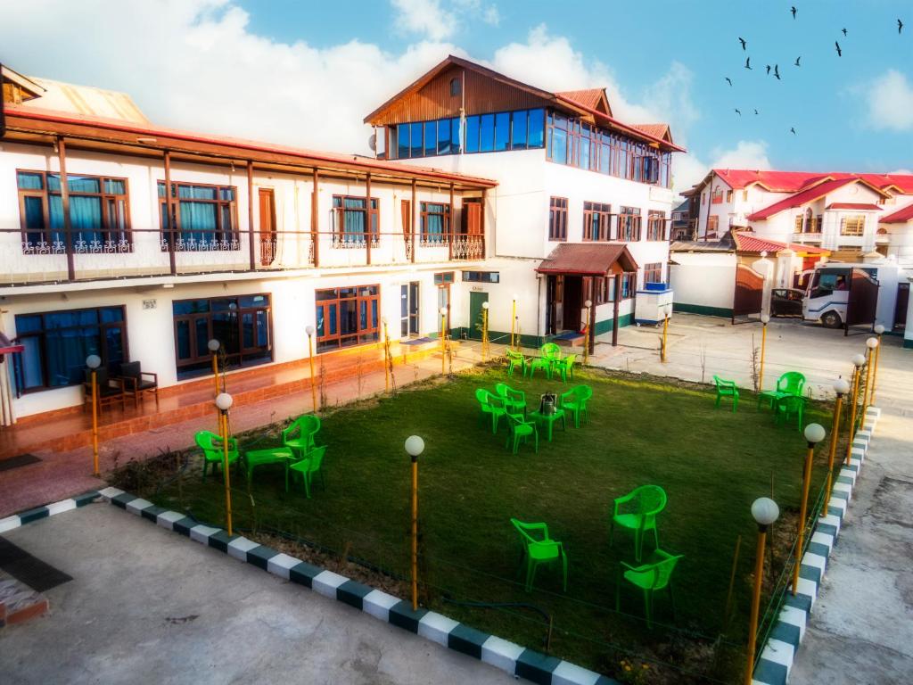 ein Gebäude mit einem Garten mit grünen Stühlen in der Unterkunft Hotel Luxury Inn in Srinagar