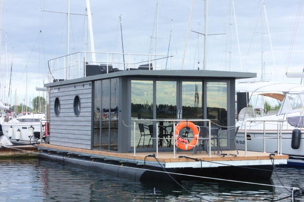 Hausboot Fjord Lacerta mit Dachterrasse in Wendtorf في Wendtorf: قارب صغير مربوط بمرسى مياه