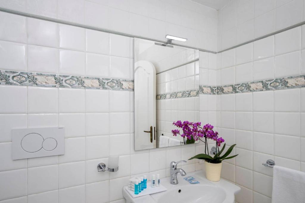 a bathroom with a sink and a mirror and purple flowers at Villa Dalu in Positano