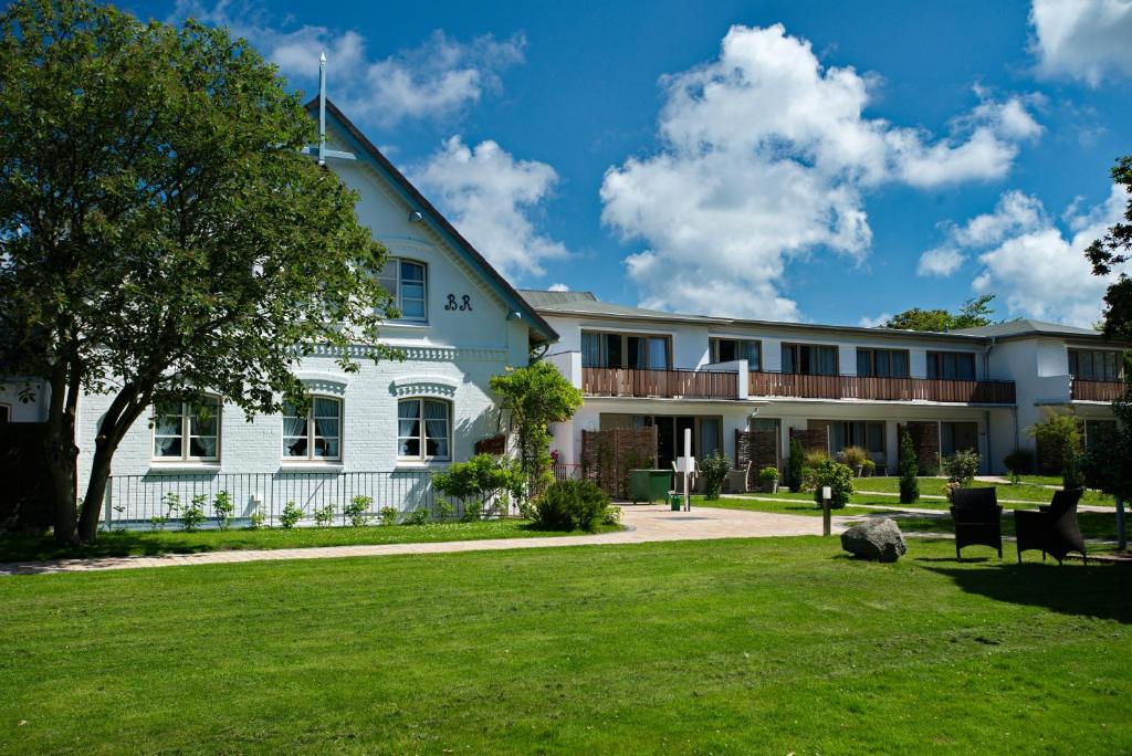 um grande edifício branco com um pátio verde em Aparthotel Friesenhof em Wenningstedt