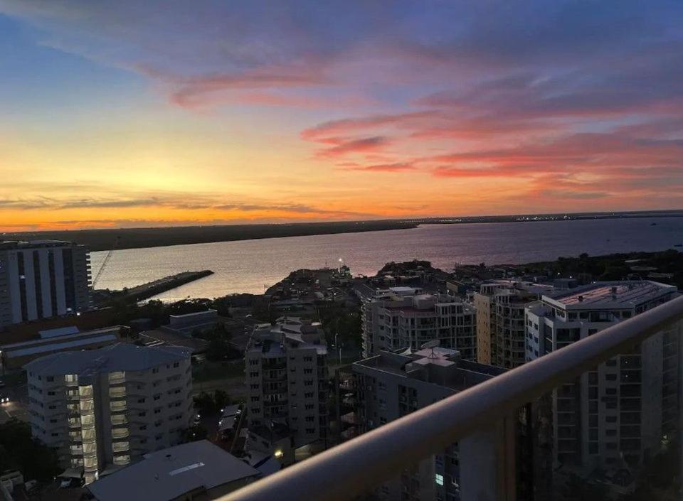 a sunset over a city with the ocean and buildings at Luxury two-beds harbour views apartment in Darwin