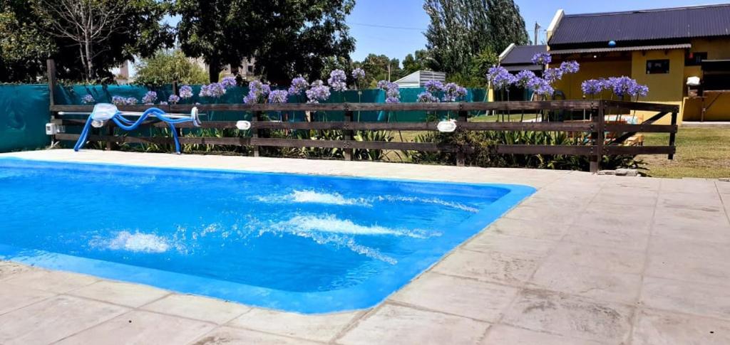 una piscina azul junto a una valla con flores púrpuras en Casa quinta Navarro en Navarro