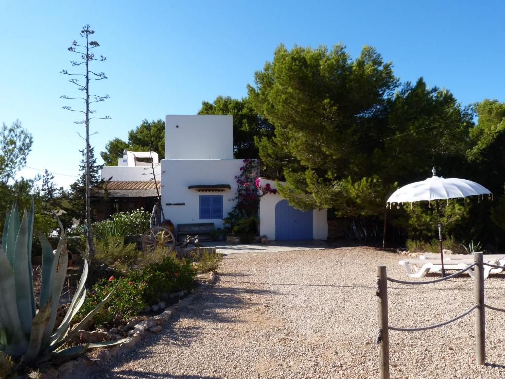 a garden with an umbrella and a house at Casa Mariposa in Es Pujols