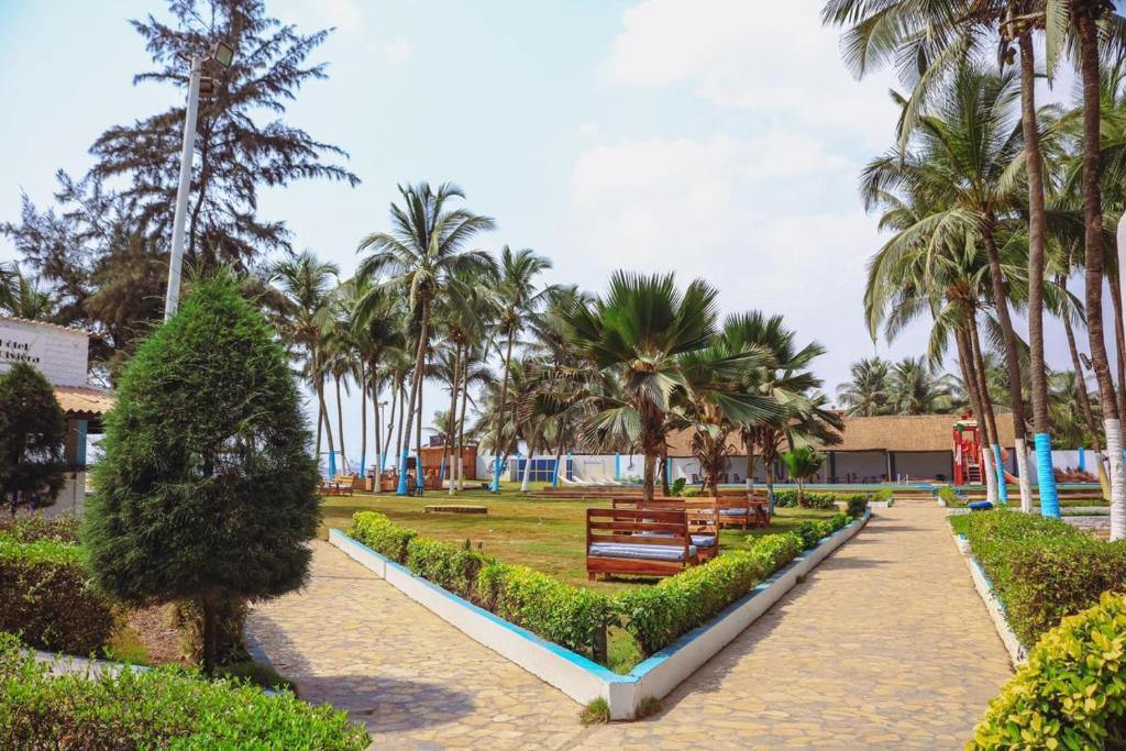 a park with benches and palm trees at Hotel Riviera Ramatou Plage in Lomé