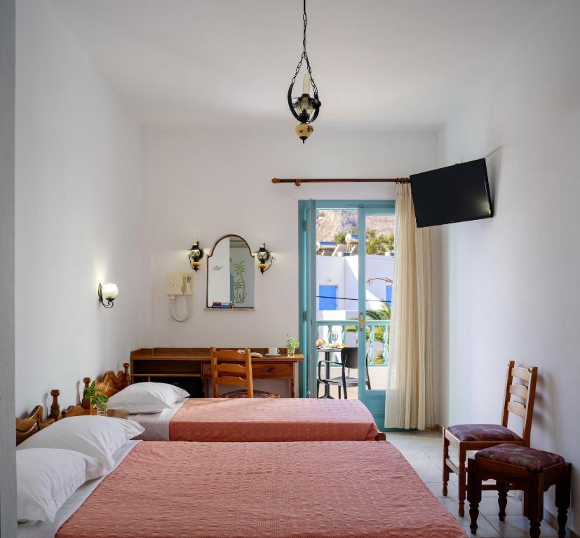 a bedroom with two beds and a desk and a window at Armonia in Kamari