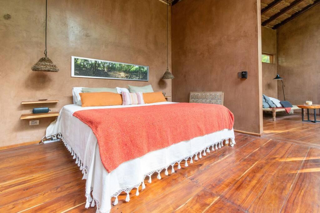 a bedroom with a large bed with an orange blanket at OJO DE AGUA. Design+pool. Vive la auténtica selva! in Tulum