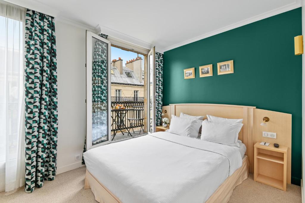 a bedroom with a large bed and a window at Hotel Elysees Opera in Paris