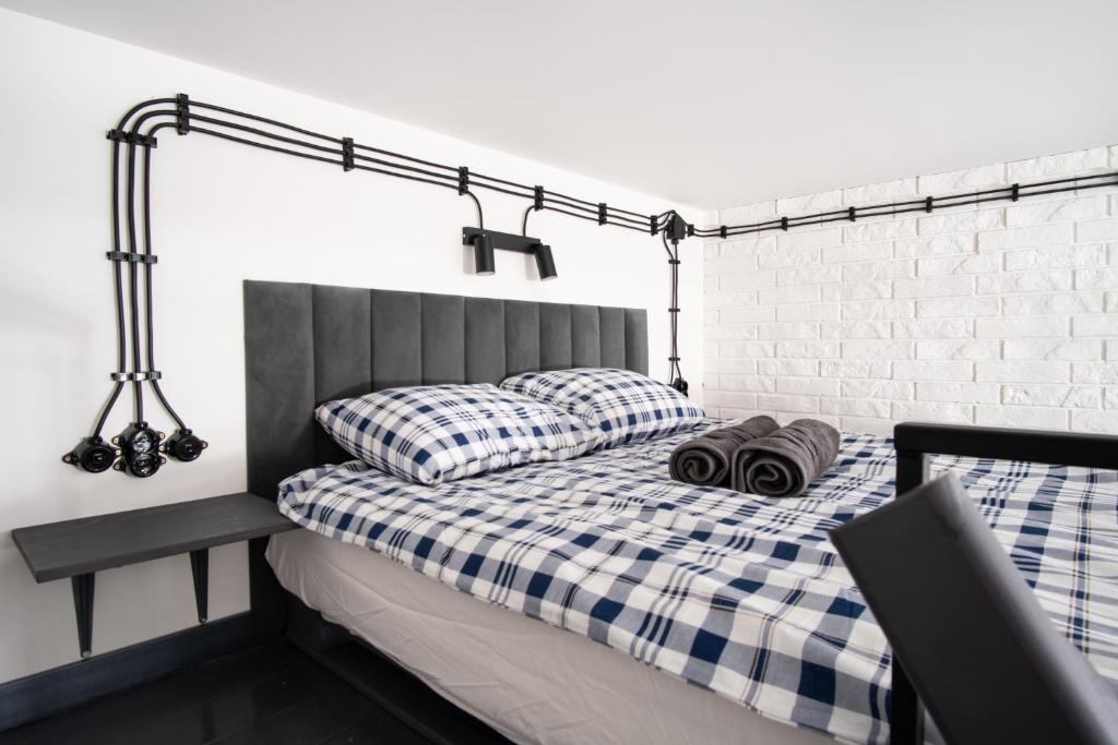 a bed with a blue and white checkered blanket and pillows at Dream Aparts - Piotrkowska 152 Select in Łódź