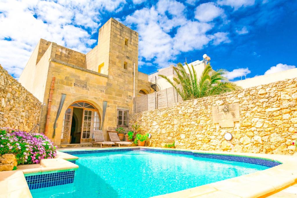 a villa with a swimming pool and a stone wall at Stunning 3 bedroom Farmhouse with pool in Xagħra
