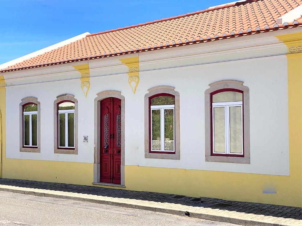 un bâtiment jaune et blanc avec une porte rouge dans l'établissement Casa do Mar Salgado, à Vila Nova De Cacela