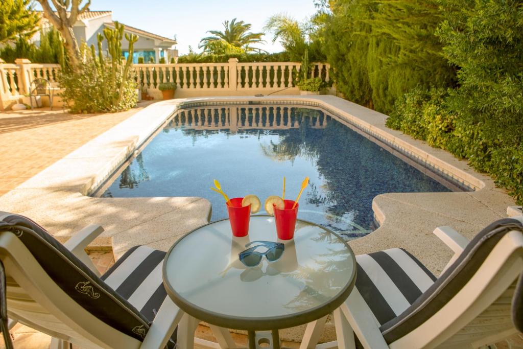 uma mesa com bebidas junto a uma piscina em La AMISTAD Apartamento en Chalet con piscina compartida em Calpe