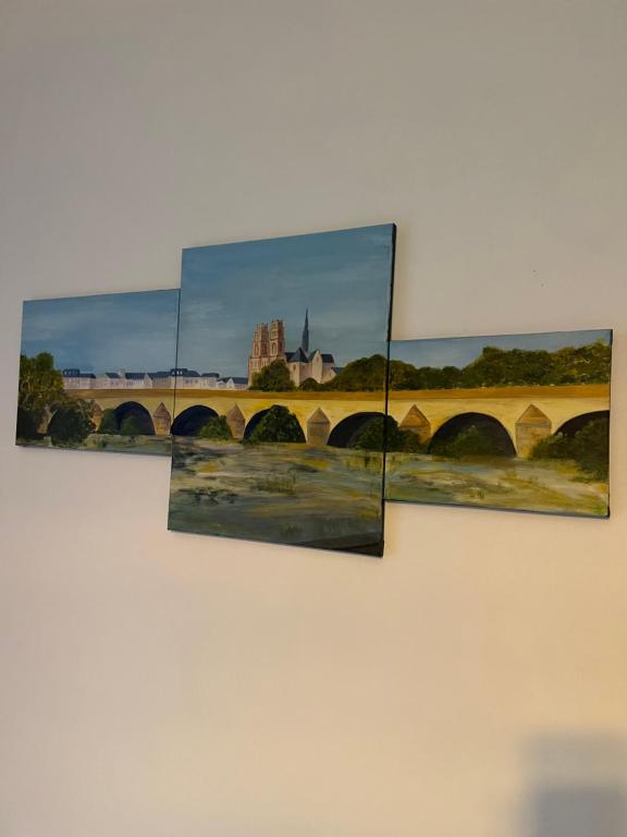 a painting of a bridge and buildings on a wall at Cosy Loire, T2 neuf, front de Loire ,vue cathédrale,5min à pied centre ville et parking privé in Orléans