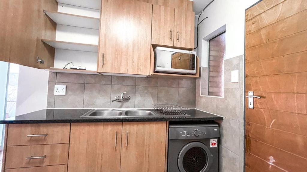 eine Küche mit einer Spüle und einer Waschmaschine in der Unterkunft Mamadou place in Johannesburg