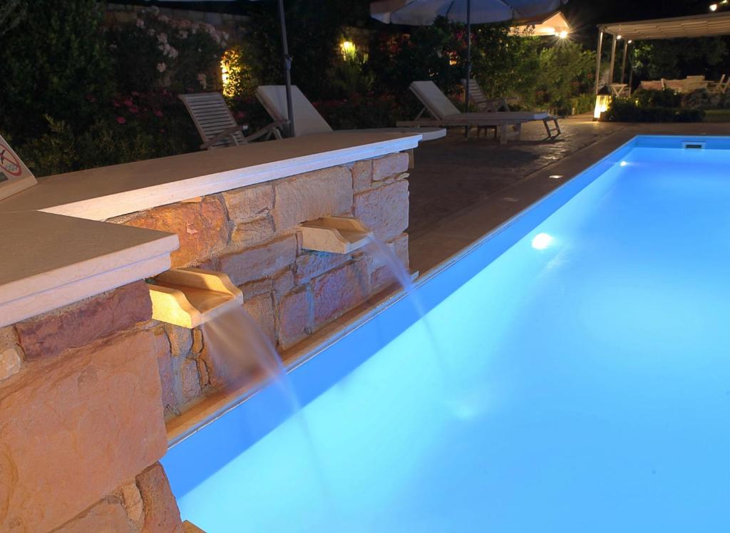 a swimming pool in a backyard at night at Venetis Luxury Apartments in Chios