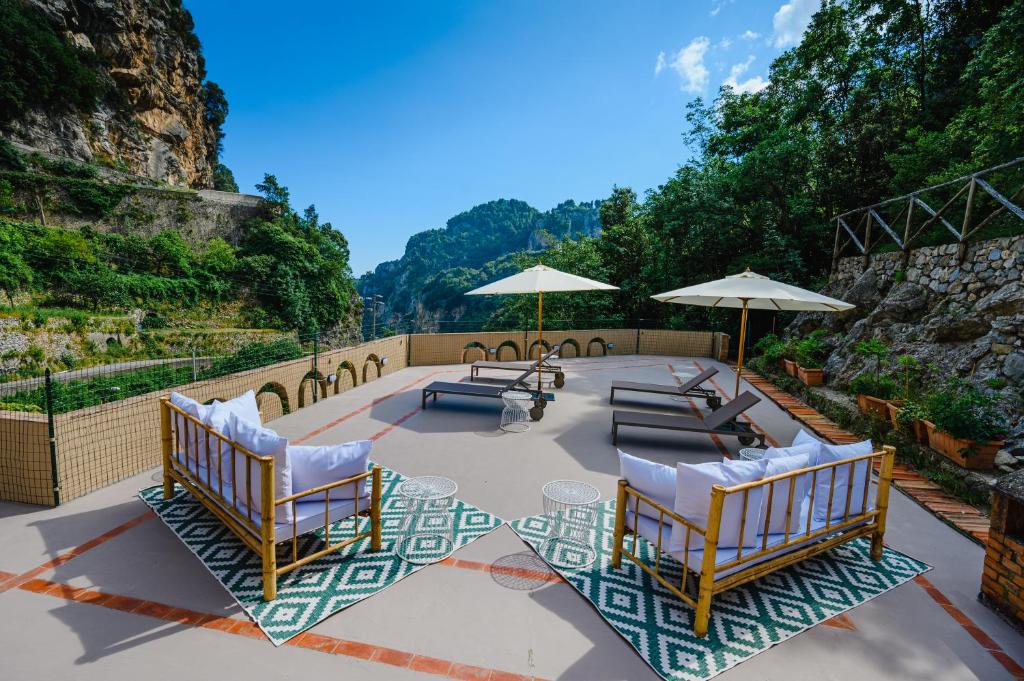 eine Terrasse mit Stühlen, Tischen und Sonnenschirmen in der Unterkunft The Lemon Garden by Elite Villas in Pontone