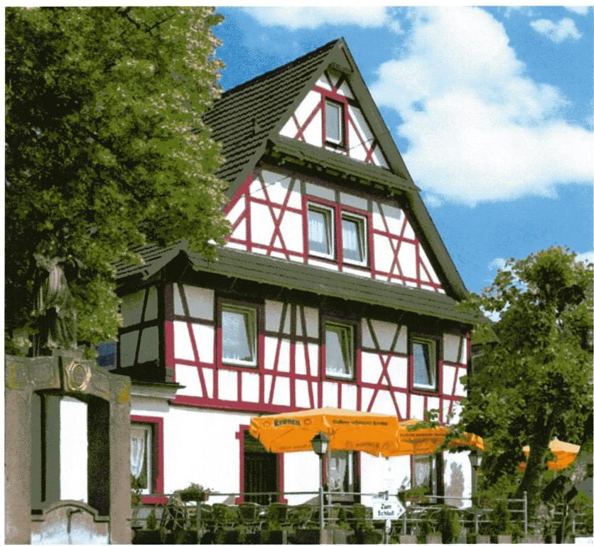 a red and white house with an orange umbrella in front at Gasthaus Ochsen in Ortenberg
