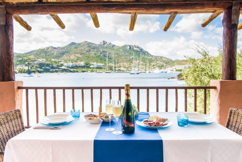 un tavolo con una bottiglia di vino e una vista sull'acqua di [Terrace on Porto Cervo] Swimming pool & private beach a Porto Cervo