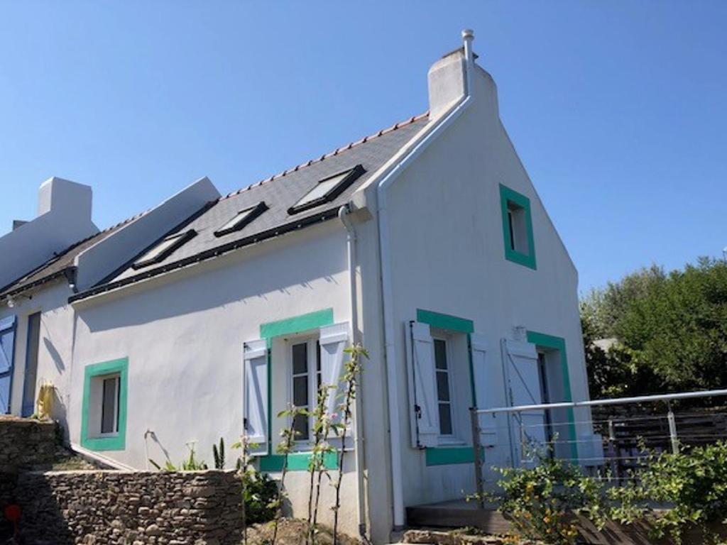 une maison blanche avec des fenêtres vertes et une clôture dans l'établissement Maison Locmaria, 3 pièces, 4 personnes - FR-1-418-91, à Locmaria