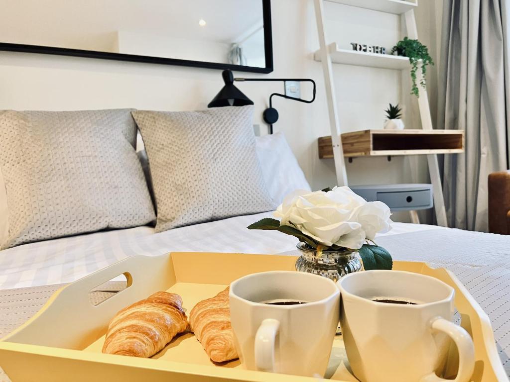 a tray with croissants and two cups on a bed at City Centre Luxury Leicester Apartment in Leicester