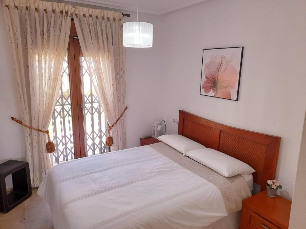 um quarto com uma cama grande e uma janela em Pool View Apartment at Jumilla III em Playa Flamenca