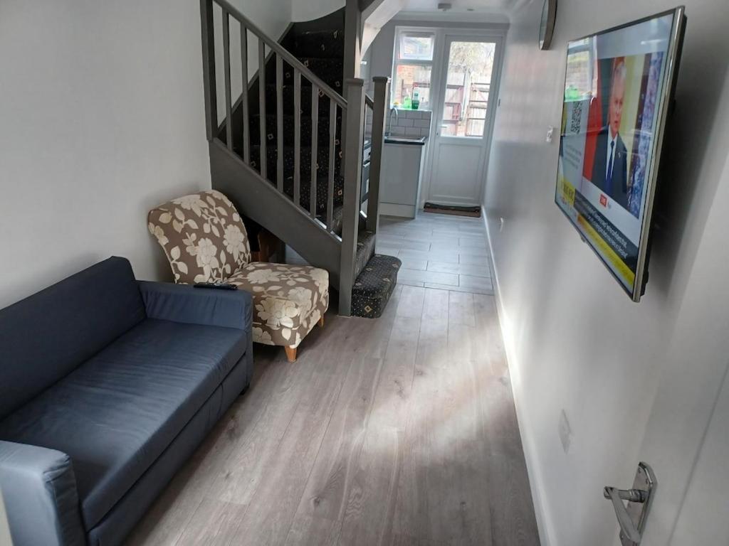 Bethel- beautiful new 1 bed house near Erith station في Erith: غرفة معيشة مع أريكة زرقاء وكرسي