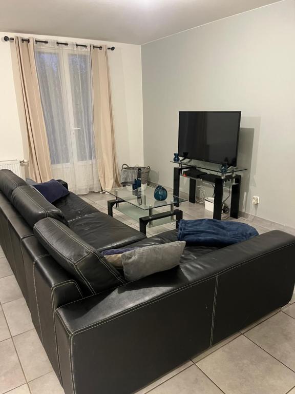 um sofá de couro preto numa sala de estar com televisão em Appartement type T3 vaulx la soie em Vaulx-en-Velin