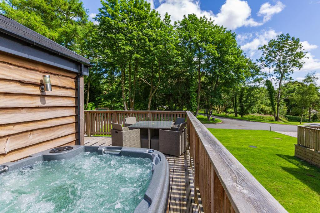 bañera de hidromasaje en la cubierta de una casa en Squirrel Lodge 41 with Hot Tub en Newton Stewart