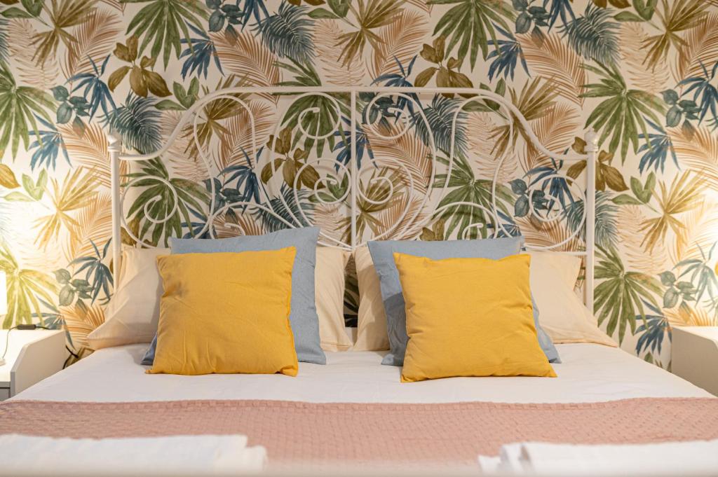 Casa Vacanze Partenope في نابولي: غرفة نوم بسرير ومخدات صفراء وورق جدران