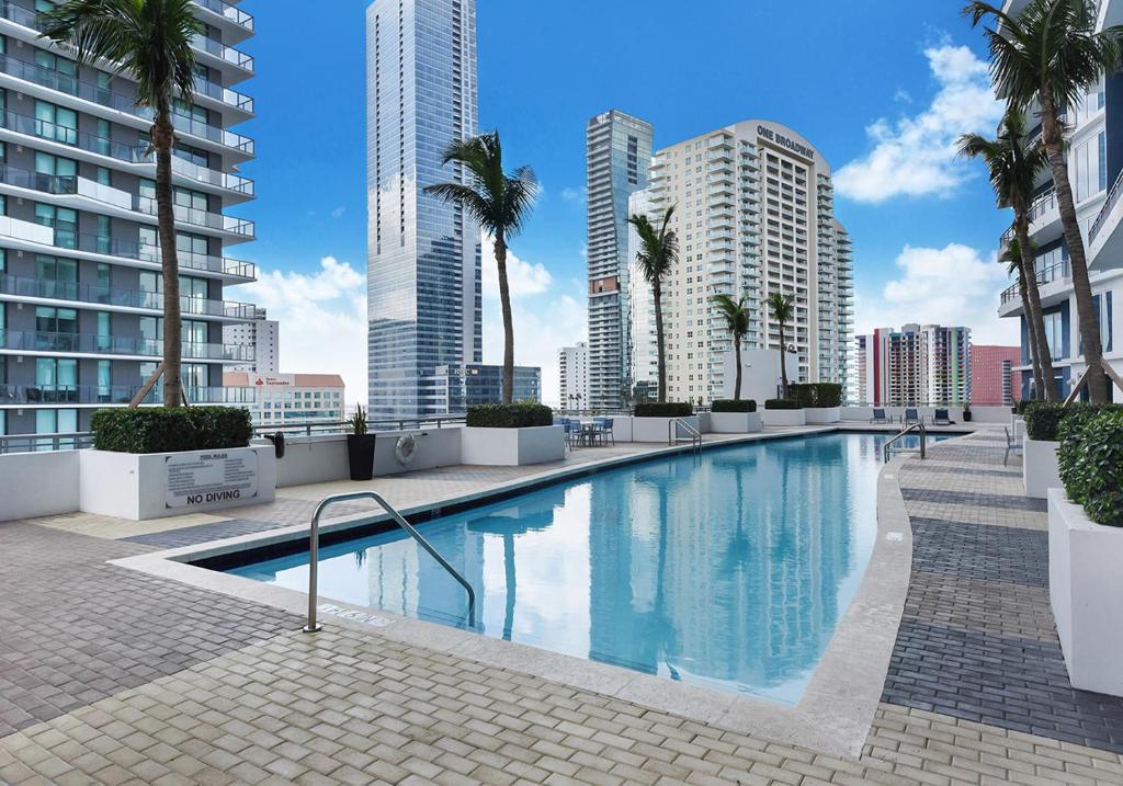 a large swimming pool with palm trees and buildings at High Floor Ocean view Unit In Brickell in Miami