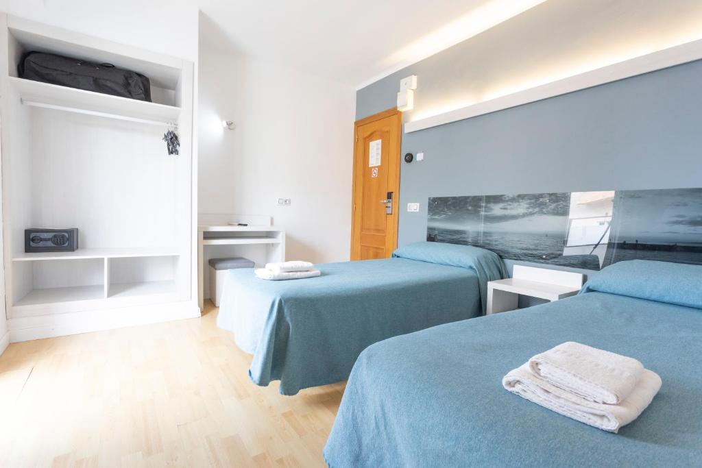 プラヤ・デ・パルマにあるHotel Raxaのブルーシーツ付きの客室内のベッド2台