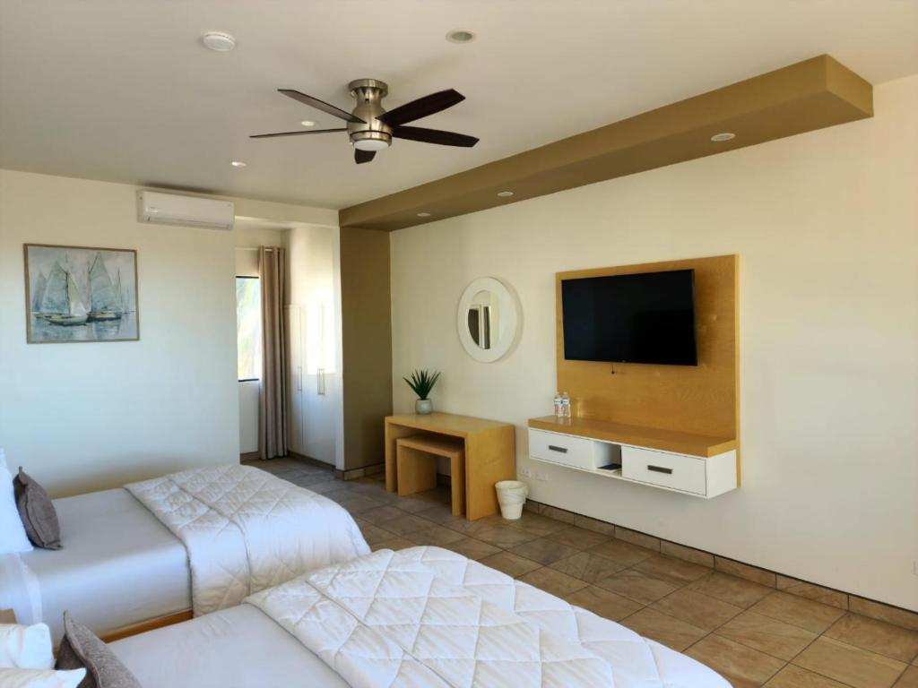 a bedroom with two beds and a flat screen tv at Hotel Paraiso Las Palmas in Ensenada