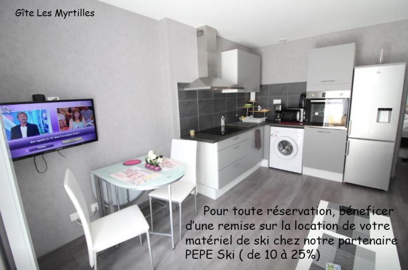 eine Küche mit einem Tisch und einem TV in einem Zimmer in der Unterkunft Gite-les-myrtilles in Corcieux
