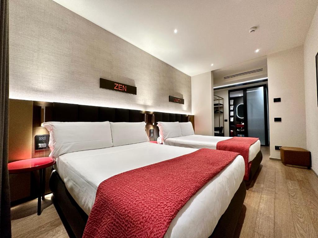 a hotel room with two beds and a clock on the wall at The Market Urban Hotel in Florence