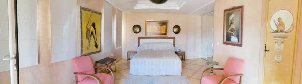 - une chambre avec un lit et deux chaises roses dans l'établissement Domaine Lamrah, à Marrakech