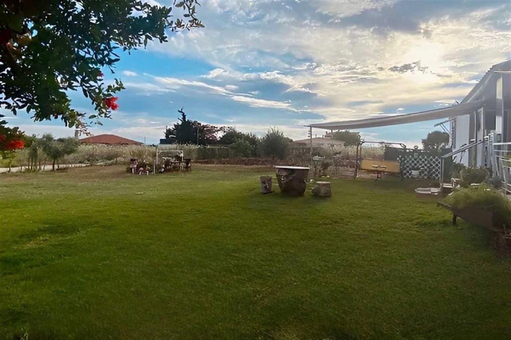 einen Hof mit grünem Gras, einem Zaun und einem Gebäude in der Unterkunft Casita Anna Maria Potidea in Nea Potidaea