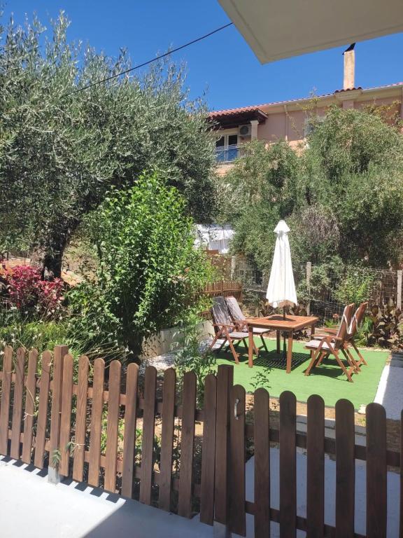 a backyard with a wooden fence and a table and chairs at Apostolos & Eleni Family Apartments in Perama