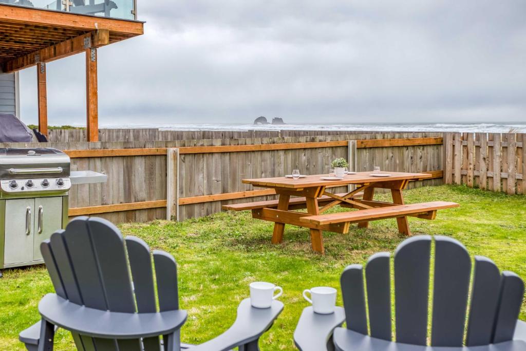 a picnic table and chairs in a backyard with the ocean at The Weather Gauge in Rockaway Beach