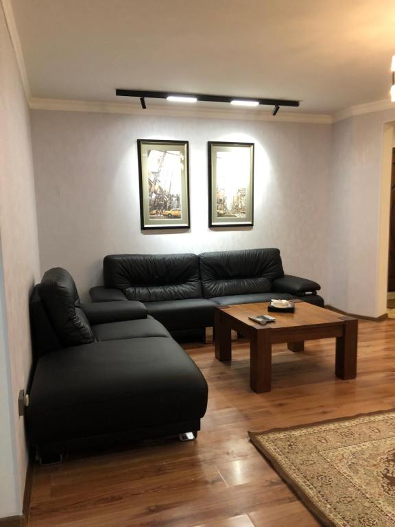 a living room with a black couch and a coffee table at Stylish apartments in the heart of the city! in Tashkent
