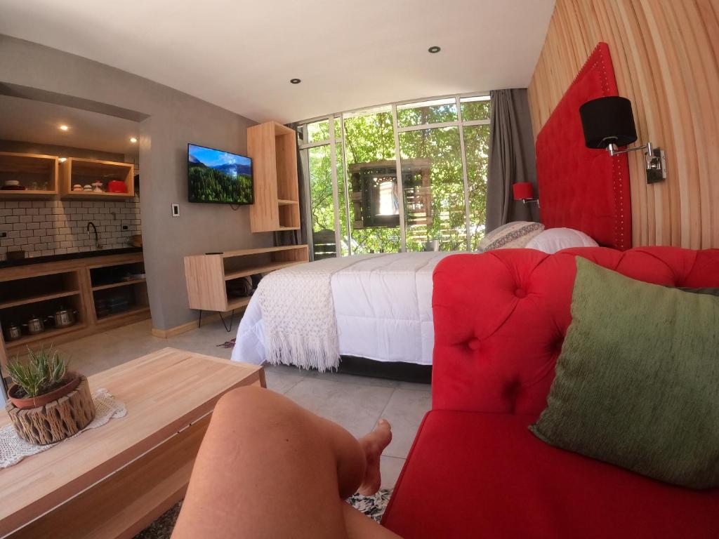 sala de estar con sofá rojo y cama en Departamento con parque a metros del mar en Ostende